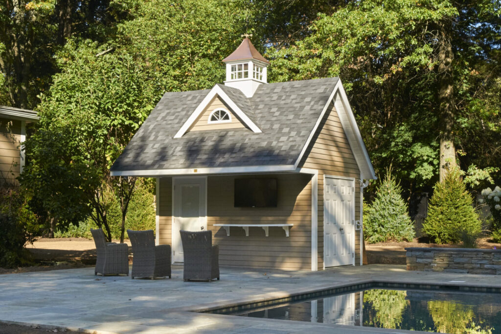 A small pool house featuring a gazebo and several chairs arranged around it, set in a tranquil outdoor environment.