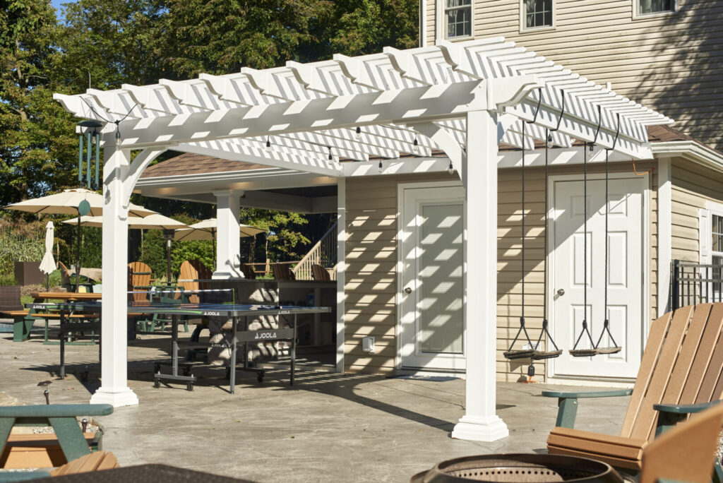 A patio featuring a wooden pergola and several chairs arranged for outdoor seating.