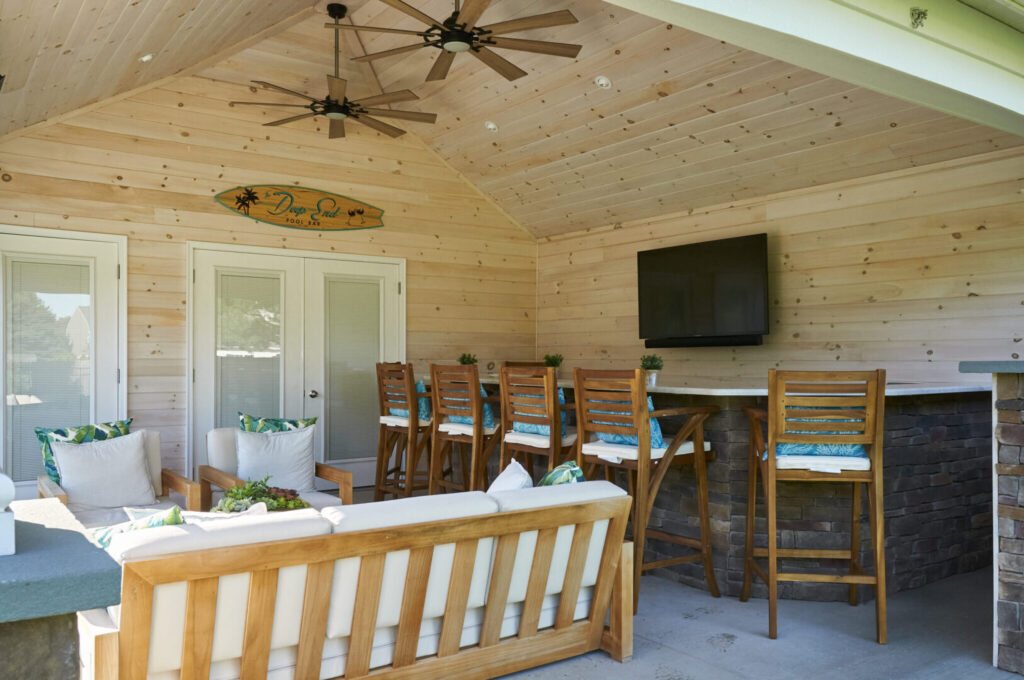 A wooden covered patio featuring a bar and several chairs for seating.
