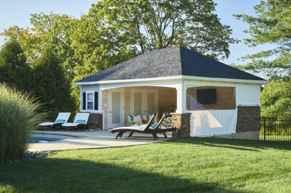 A small gazebo beside a pool, surrounded by lawn chairs, creating a relaxing outdoor space.