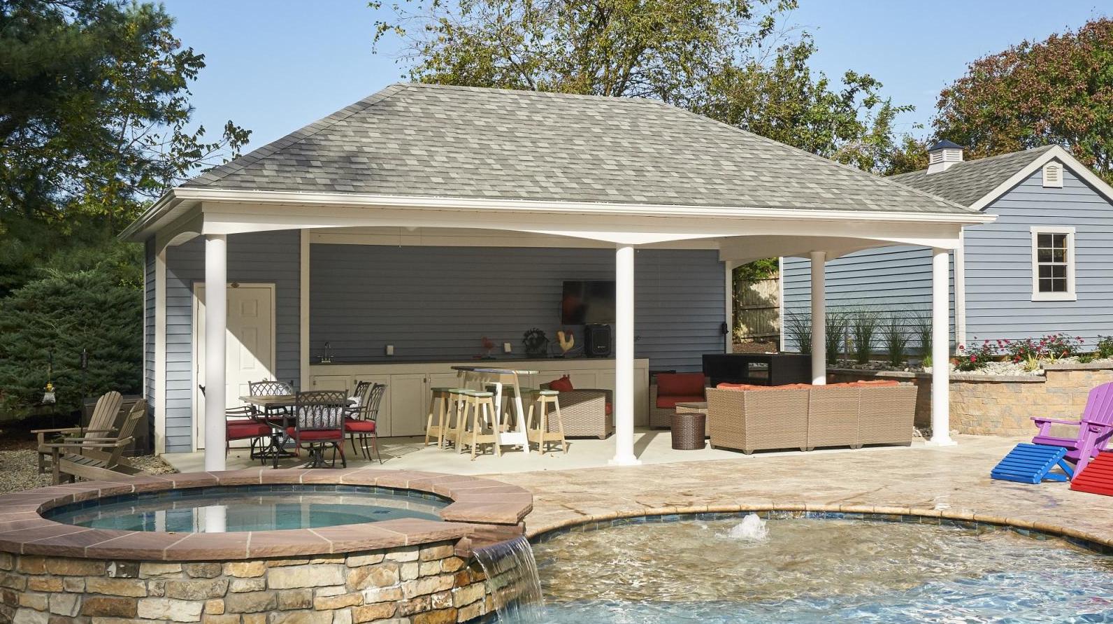 A pool house featuring a gazebo and a spacious patio surrounded by greenery.