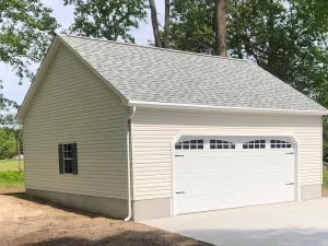 A garage featuring white siding and a white roof, set against a clear blue sky.