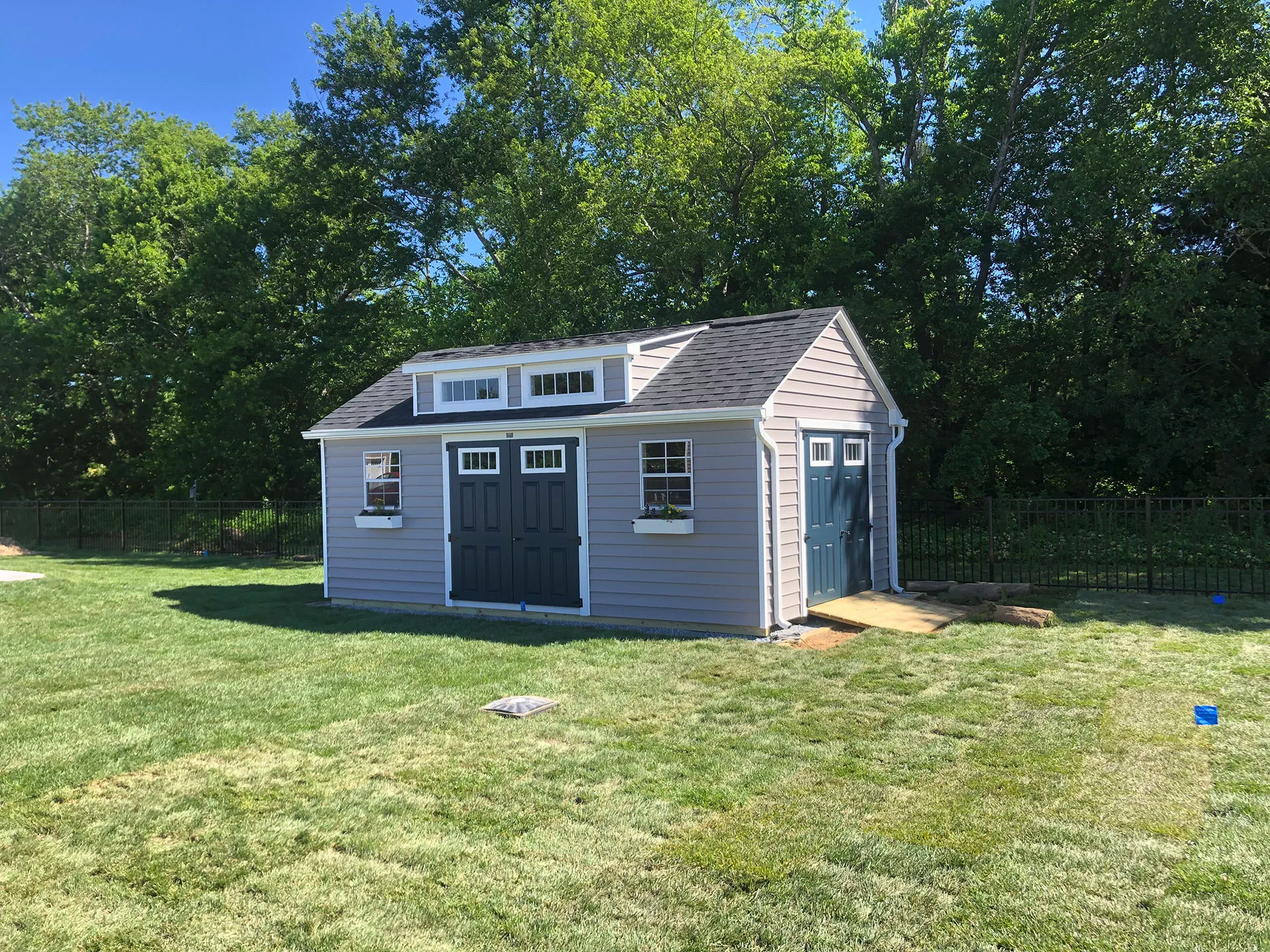 A small shed featuring a sloped roof and two doors, set against a simple outdoor background.