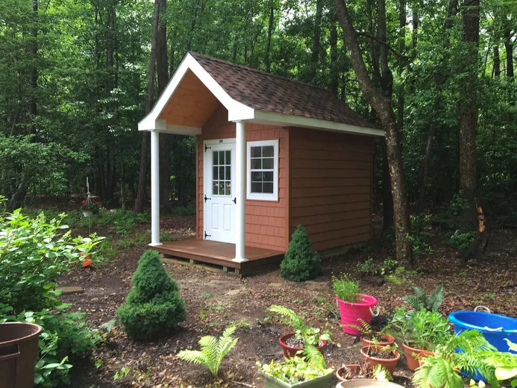 A small shed featuring a black door and windows, set against a neutral background.