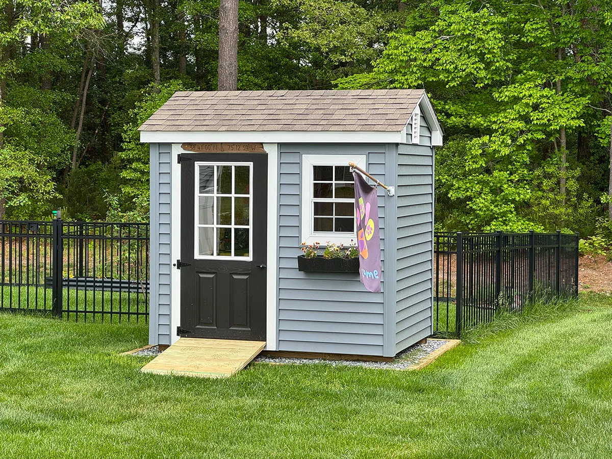 A small blue shed featuring a door and a window, set against a neutral background.