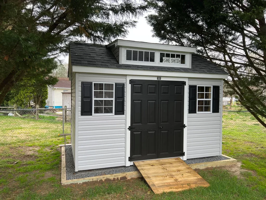 A small shed featuring a door and two windows, set against a natural background.