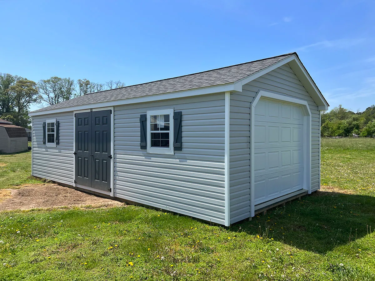 A small garage with its door open, revealing the interior space and tools inside.