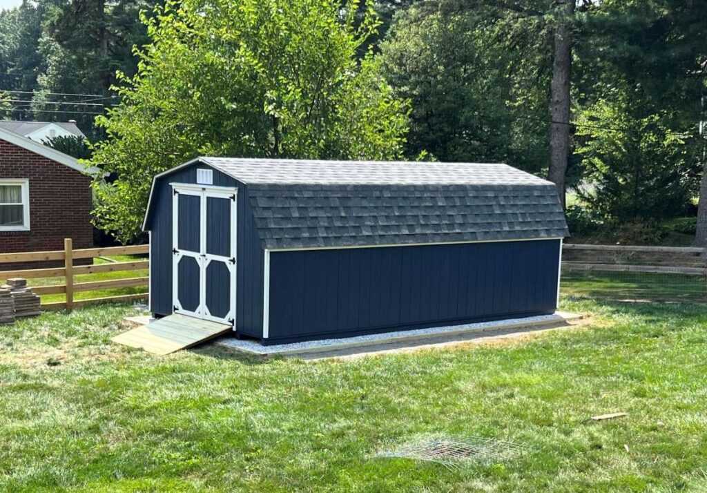 A blue shed featuring a white door and a white roof, set against a clear sky.