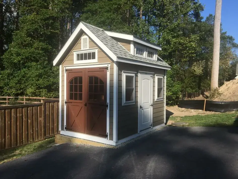 A small shed featuring a door and a window, set against a simple outdoor background.