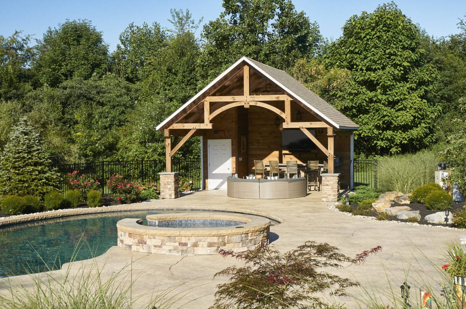 A serene backyard featuring a pool and gazebo surrounded by lush trees and shrubs.