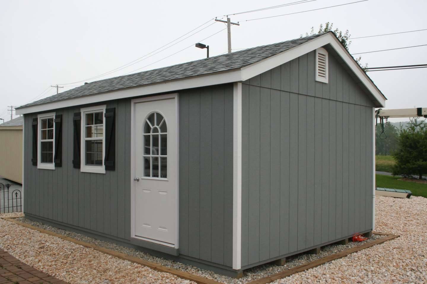 A small gray shed featuring a white door, set against a neutral background.