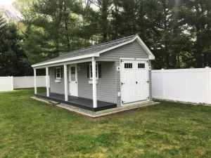 A small shed surrounded by a white fence and a charming white picket fence.