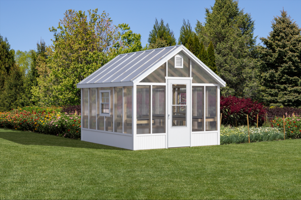 A small greenhouse located in the center of a vast green field under a clear blue sky.